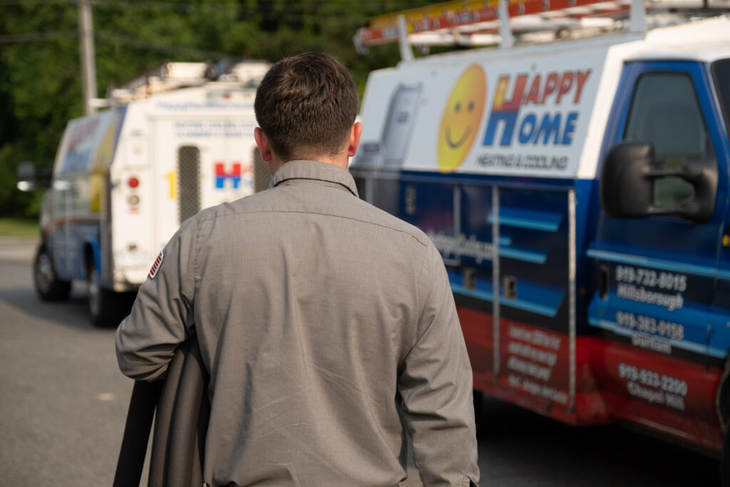 A technician walking toward a service truck after completing an HVAC service call in Durham, NC